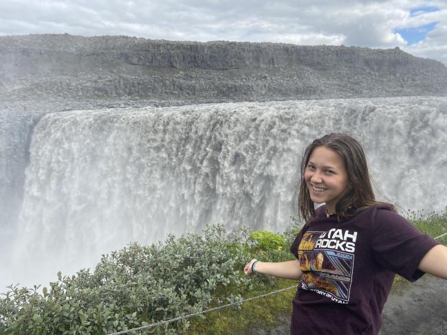Photo of Saskia exploring the Dettifoss Waterfall in Iceland and wearing one of her prized Geography pun T-shirts